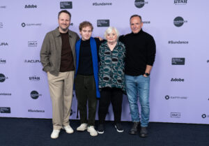 Four people stand for a photo against a Sundance Film Festival backdrop.